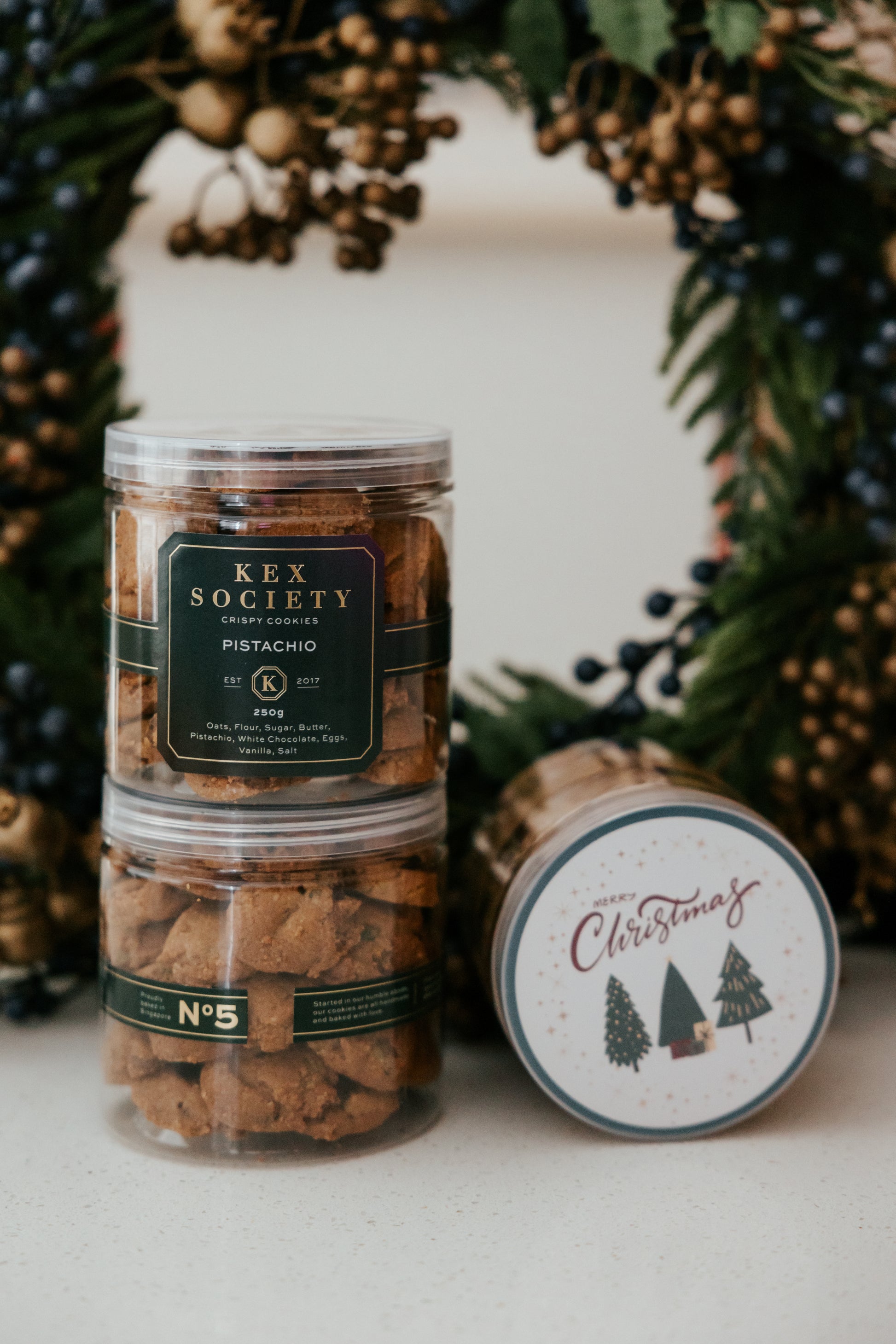 2 bottles of Kex Society pistachio cookies in a decorative setting.